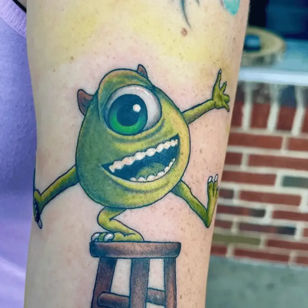 Mike Wazowski tattoo with bold outlines on the upper arm