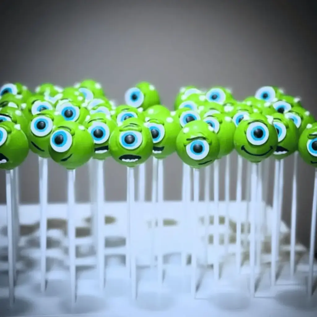 Green Mike Wazowski cake pops decorated with one eye, smiles and small horns