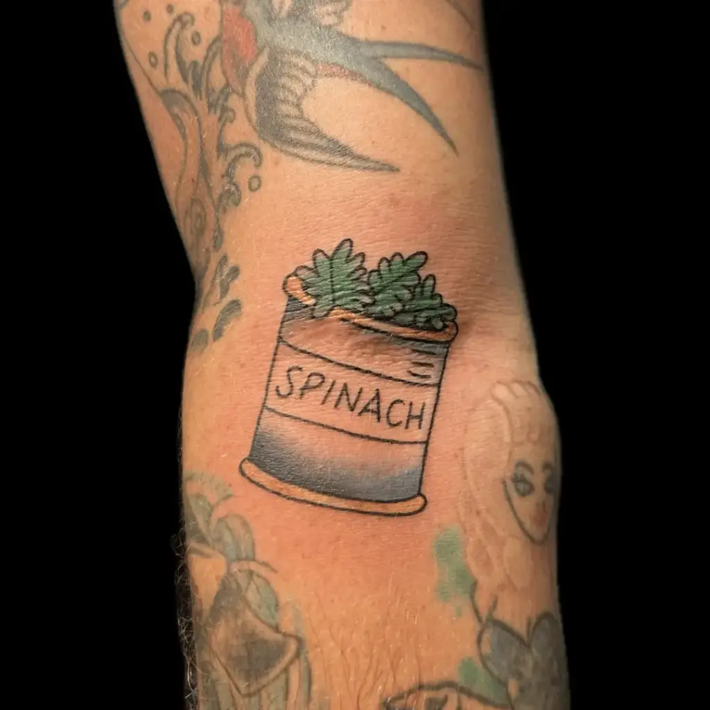 Popeye tattoo featuring a can of spinach and flexing pose